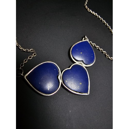 255 - A 925 silver triple heart necklace, each heart is inset with a lapislazuli stone presenting a vibran... 