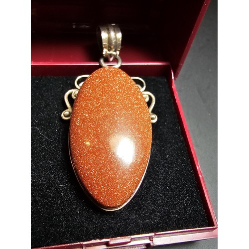 271 - A large 925 silver pendant inset with a large oval gold stone presenting a vibrant orange colour wit... 