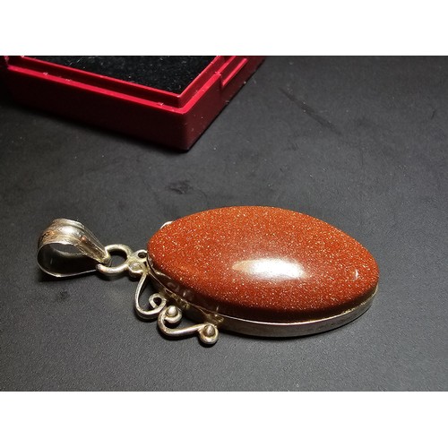 271 - A large 925 silver pendant inset with a large oval gold stone presenting a vibrant orange colour wit... 