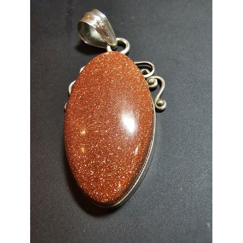 271 - A large 925 silver pendant inset with a large oval gold stone presenting a vibrant orange colour wit... 