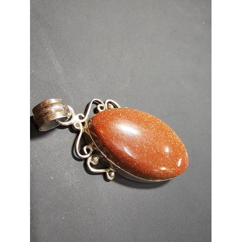 271 - A large 925 silver pendant inset with a large oval gold stone presenting a vibrant orange colour wit... 