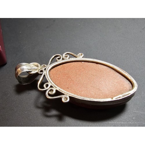 271 - A large 925 silver pendant inset with a large oval gold stone presenting a vibrant orange colour wit... 