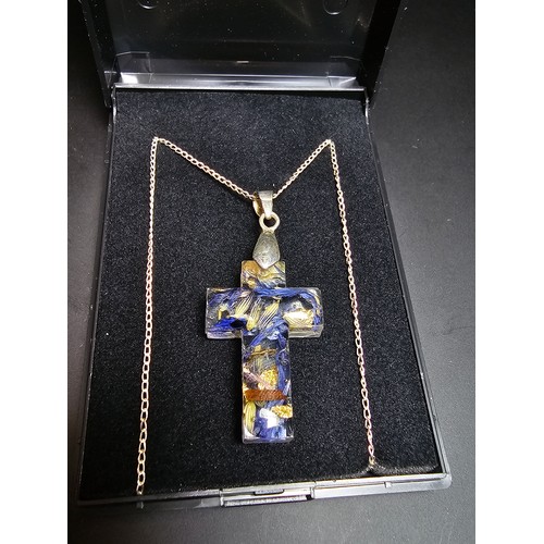 273 - An unusual cross pendant made out of resin inset with real dried flowers and gold leaf set on a 925 ... 