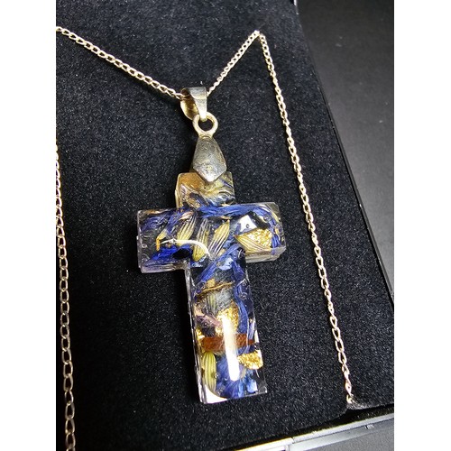 273 - An unusual cross pendant made out of resin inset with real dried flowers and gold leaf set on a 925 ... 