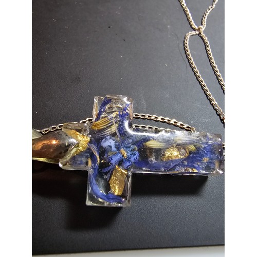 273 - An unusual cross pendant made out of resin inset with real dried flowers and gold leaf set on a 925 ... 