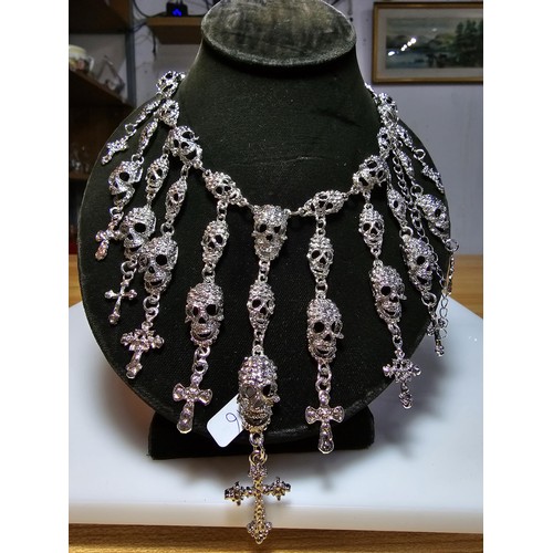 311 - An unusual silver tone ornate necklace featuring a large quantity of skull and cross drops. Beautifu... 