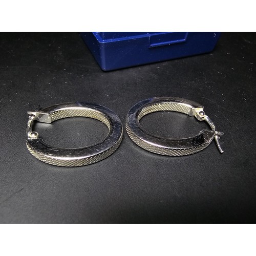 211 - Pair of hallmarked 9ct. white gold hoop earrings with a machine engraved design to the inside and ou... 