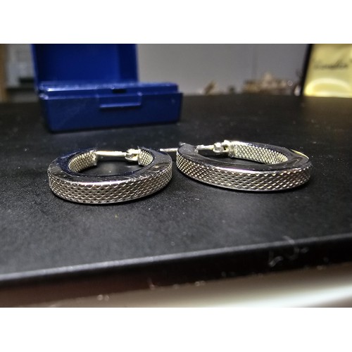 211 - Pair of hallmarked 9ct. white gold hoop earrings with a machine engraved design to the inside and ou... 