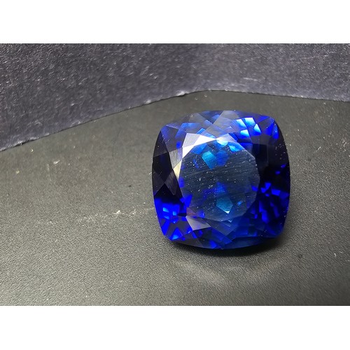 251 - A cased large lab created cushion cut faceted blue sapphire gemstone complete with its presentation ... 