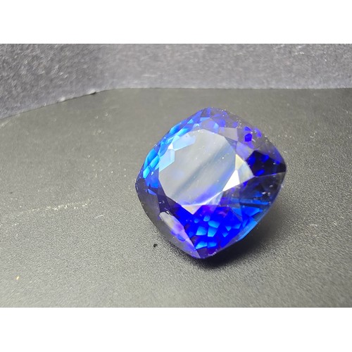 251 - A cased large lab created cushion cut faceted blue sapphire gemstone complete with its presentation ... 