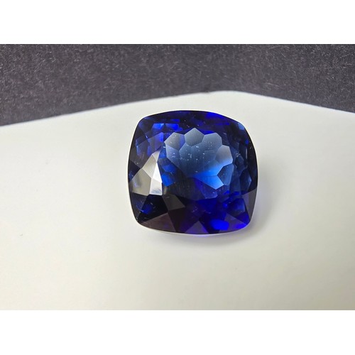 251 - A cased large lab created cushion cut faceted blue sapphire gemstone complete with its presentation ... 