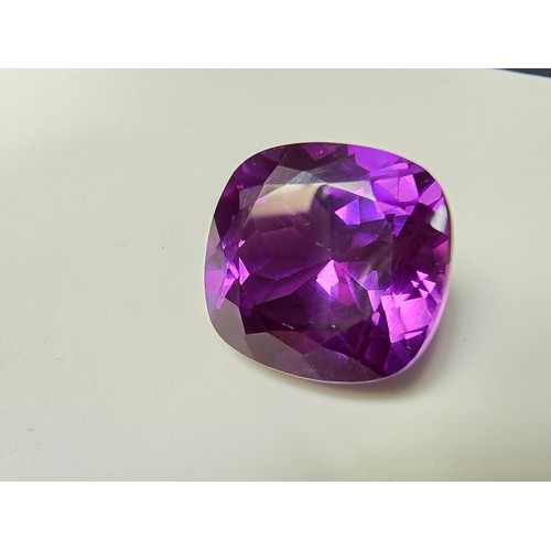 254 - A cased large lab created cushion cut faceted purple sapphire gemstone complete with its presentatio... 