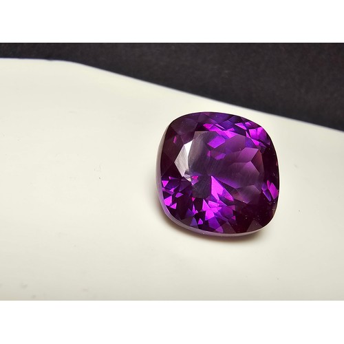 254 - A cased large lab created cushion cut faceted purple sapphire gemstone complete with its presentatio... 