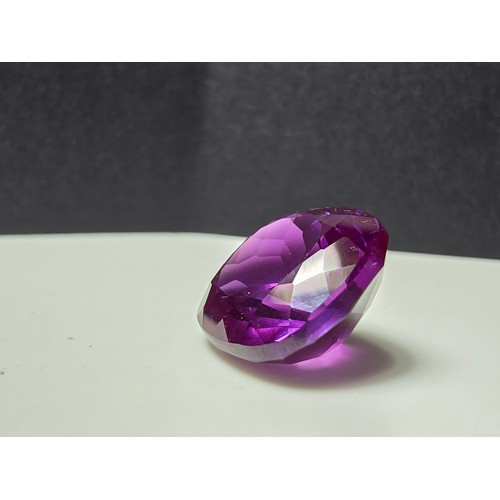 254 - A cased large lab created cushion cut faceted purple sapphire gemstone complete with its presentatio... 