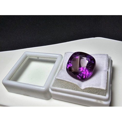 254 - A cased large lab created cushion cut faceted purple sapphire gemstone complete with its presentatio... 