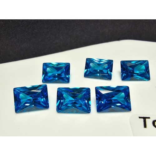 258 - A collection of 10x lab created faceted aqua marine gemstones, rectangular cut and oval cut stones. ... 