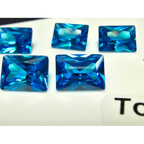 258 - A collection of 10x lab created faceted aqua marine gemstones, rectangular cut and oval cut stones. ... 