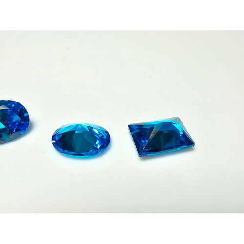 258 - A collection of 10x lab created faceted aqua marine gemstones, rectangular cut and oval cut stones. ... 