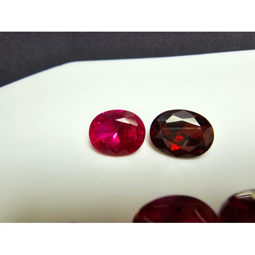 260 - A collection of 9x lab created faceted ruby gemstones along with a faceted almandine garnet gemstone... 