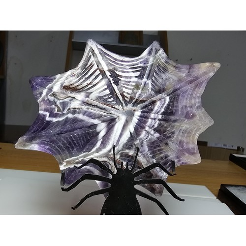 220 - An unusual crystal ornament of a large carved natural amethyst cobweb which sits on a black metal st... 