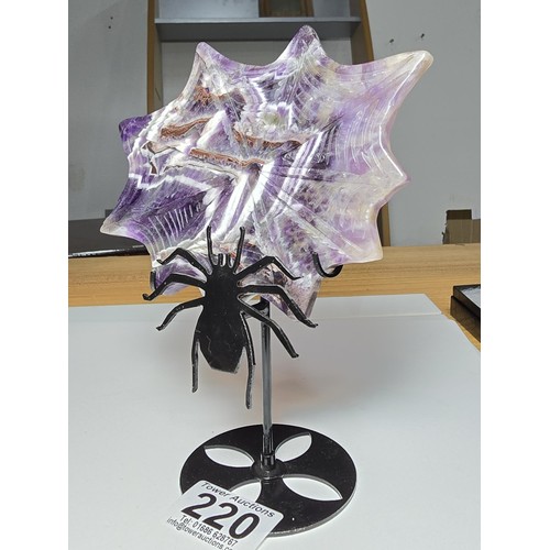 220 - An unusual crystal ornament of a large carved natural amethyst cobweb which sits on a black metal st... 