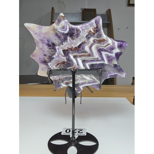 220 - An unusual crystal ornament of a large carved natural amethyst cobweb which sits on a black metal st... 