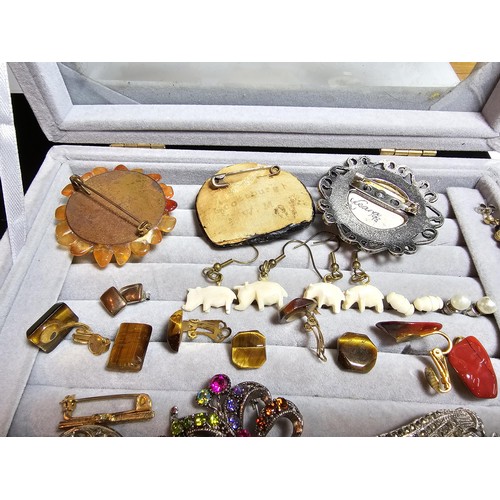 226 - A ring display box containing a large quantity of costume jewellery which includes ornate brooches, ... 