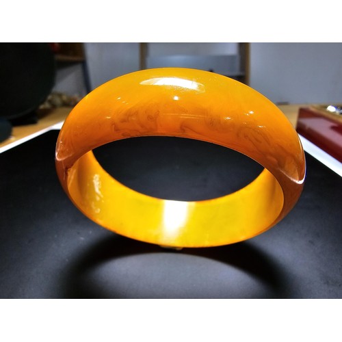 229C - A good quality genuine solid butterscotch amber carved bangle presenting an excellent natural swirle... 