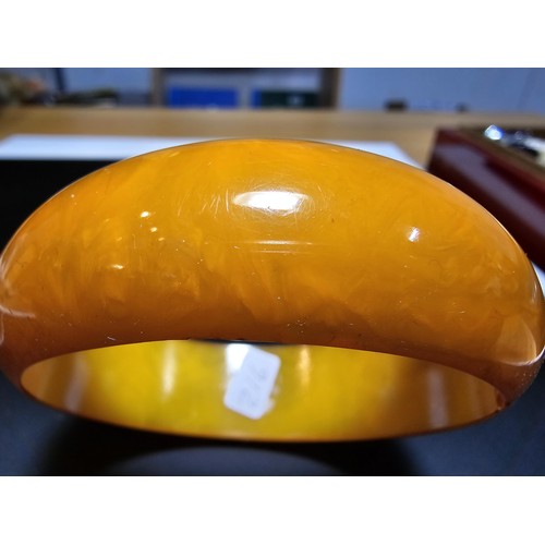 229C - A good quality genuine solid butterscotch amber carved bangle presenting an excellent natural swirle... 