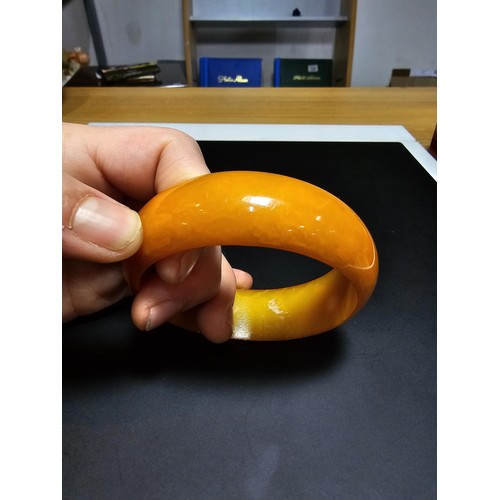 229C - A good quality genuine solid butterscotch amber carved bangle presenting an excellent natural swirle... 