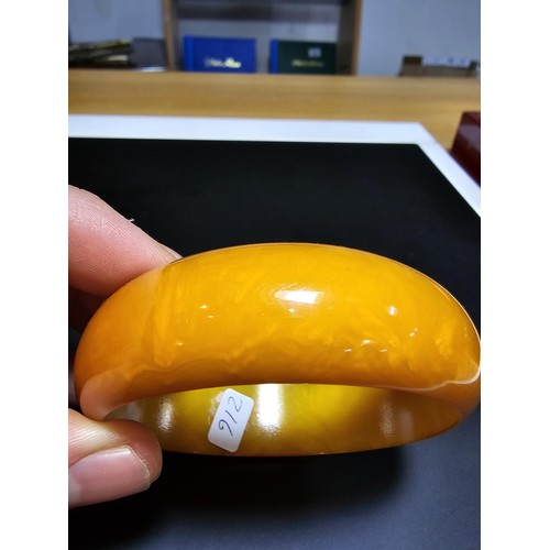 229C - A good quality genuine solid butterscotch amber carved bangle presenting an excellent natural swirle... 