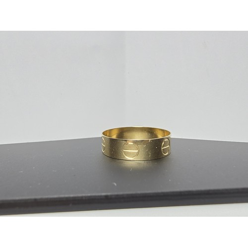 219 - An 18ct yellow gold ring with a Flathead screw design all the way around in the style of a designer ... 