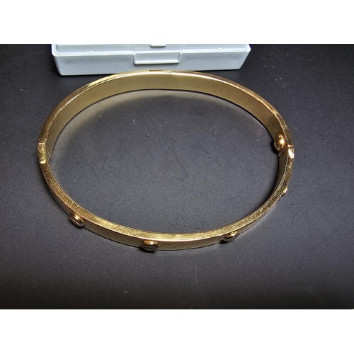 220 - An 18ct yellow gold bangle with a Flathead screw design all the way around, in the style of a design... 