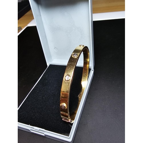 220 - An 18ct yellow gold bangle with a Flathead screw design all the way around, in the style of a design... 