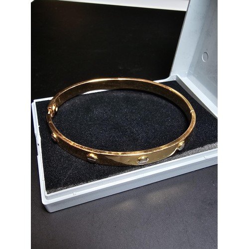 220 - An 18ct yellow gold bangle with a Flathead screw design all the way around, in the style of a design... 