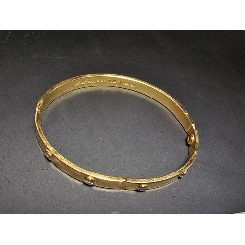 220 - An 18ct yellow gold bangle with a Flathead screw design all the way around, in the style of a design... 