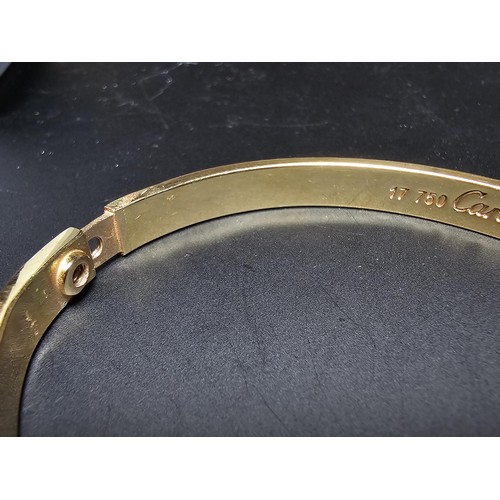 220 - An 18ct yellow gold bangle with a Flathead screw design all the way around, in the style of a design... 