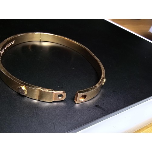 220 - An 18ct yellow gold bangle with a Flathead screw design all the way around, in the style of a design... 