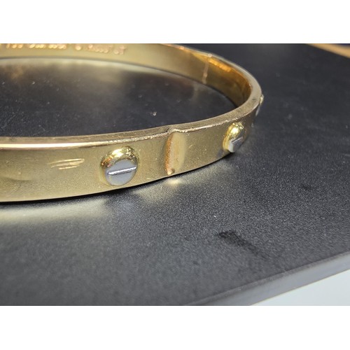 220 - An 18ct yellow gold bangle with a Flathead screw design all the way around, in the style of a design... 