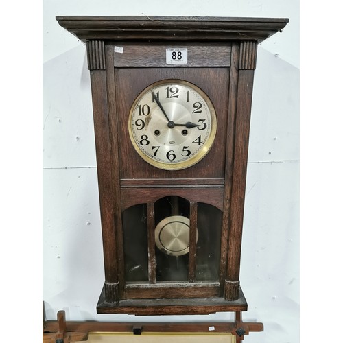 88 - Vintage oak wall clock complete with pendulum and key. Measures 68cm x 33.5cm x 18cm.