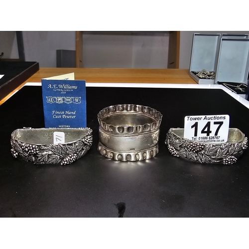 147 - A hallmarked silver napkin ring along with a pair of ornate hand cast pewter napkin rings with a gra... 