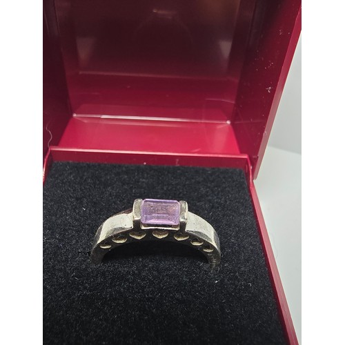 138 - A pretty 925 silver ring inset with a faceted baguette cut amethyst gemstone with a pierced heart de... 