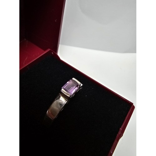 138 - A pretty 925 silver ring inset with a faceted baguette cut amethyst gemstone with a pierced heart de... 