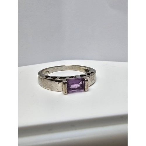 138 - A pretty 925 silver ring inset with a faceted baguette cut amethyst gemstone with a pierced heart de... 