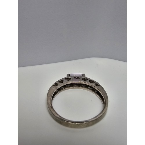 138 - A pretty 925 silver ring inset with a faceted baguette cut amethyst gemstone with a pierced heart de... 