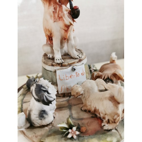 113 - Vintage Capodimonte figure of a dog with a tobacco pipe sitting on a barrel with dogs playing around... 