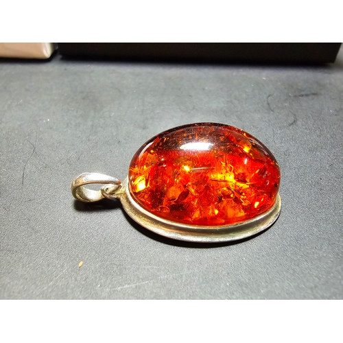 172 - A good quality 925 silver pendant inset with a large oval natural amber stone with inclusions, featu... 