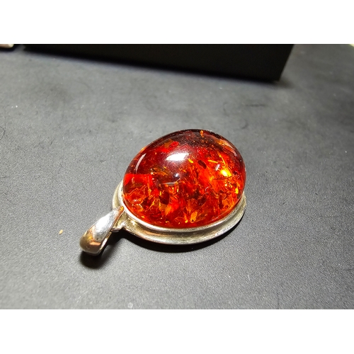 172 - A good quality 925 silver pendant inset with a large oval natural amber stone with inclusions, featu... 