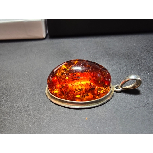 172 - A good quality 925 silver pendant inset with a large oval natural amber stone with inclusions, featu... 