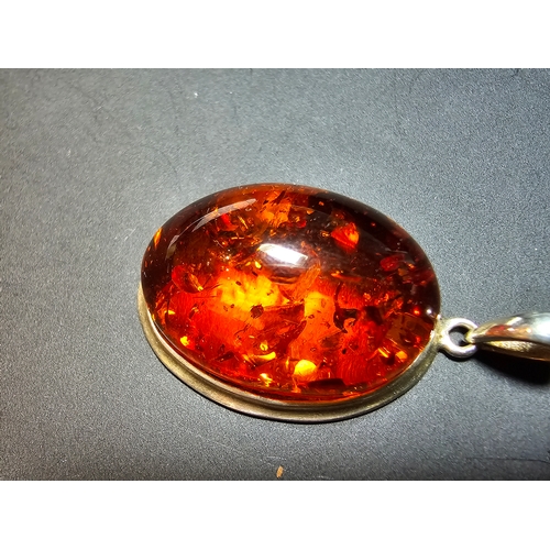 172 - A good quality 925 silver pendant inset with a large oval natural amber stone with inclusions, featu... 